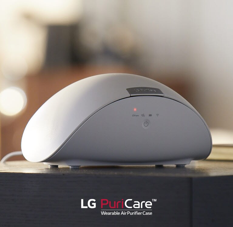 علبة جهاز تنقية الهواء القابل للارتداء LG PuriCare™ موضوعة على طاولة. يضيء ضوء أحمر على الشاشة. 