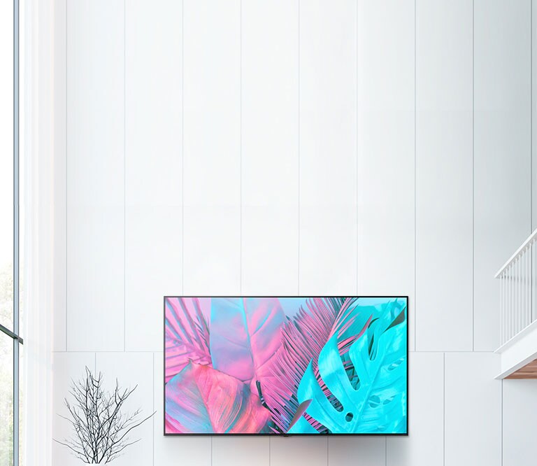 شاشة تلفاز مسطحة كبيرة مثبتة على حائط أبيض.  تعرض الشاشة أوراقاً كبيرة بألوان زاهية. 