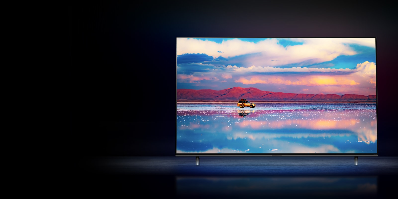 تلفاز LG NanoCell على خلفية سوداء.  يعرض التلفاز سيارة تسير أمام سلسلة جبال منخفضة في المياه التي تعكس السماء المفعمة بالحيوية. 
