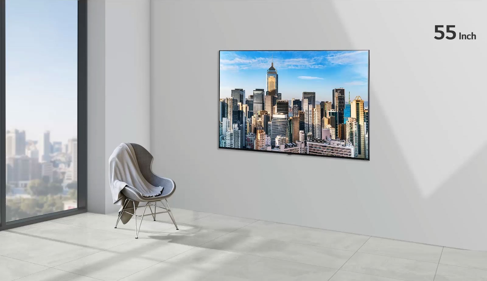 شاشة تلفاز مسطحة مثبتة على جدار رمادي بجوار نافذة من الأرض إلى السقف وكرسي.  تعرض الشاشة منظرًا للمدينة مقابل السماء الزرقاء ويزداد حجم التلفاز من 55 بوصة إلى 86 بوصة. 
