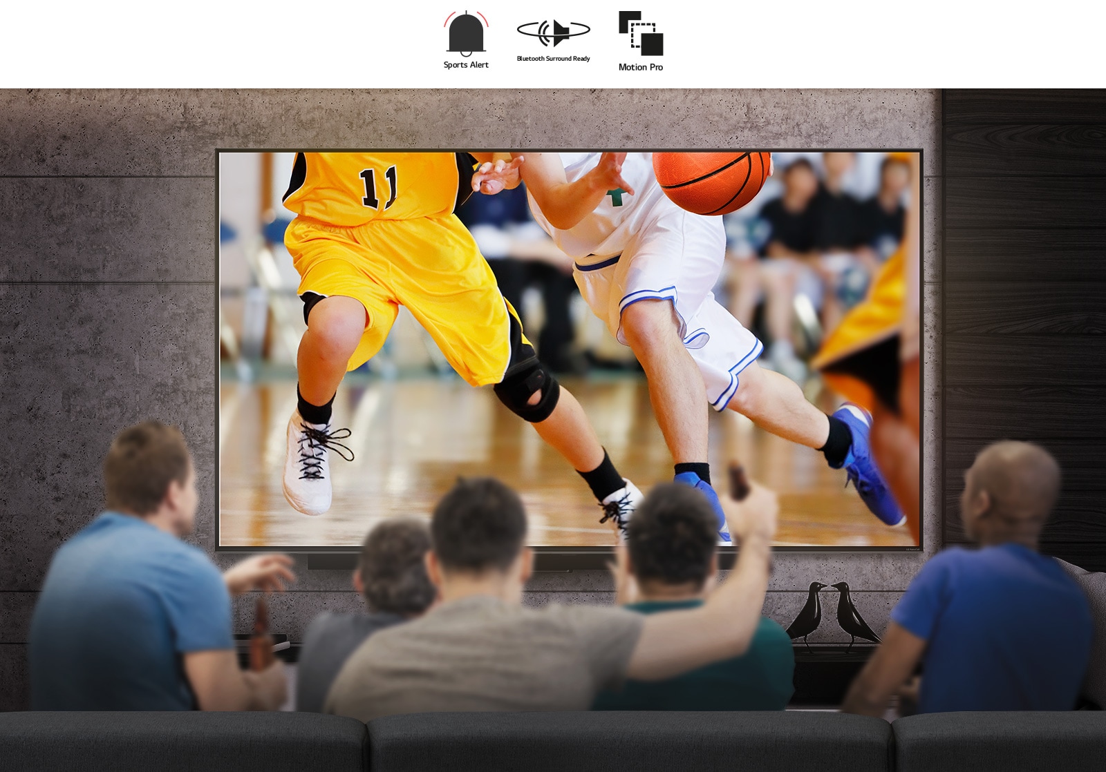 منظر خلفي لمجموعة من الرجال يجلسون أمام تلفاز كبير معلق على الحائط.  يظهر على الشاشة مجموعة من لاعبي كرة السلة. 