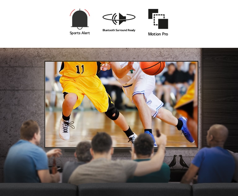 منظر خلفي لمجموعة من الرجال يجلسون أمام تلفاز كبير معلق على الحائط.  يظهر على الشاشة مجموعة من لاعبي كرة السلة. 