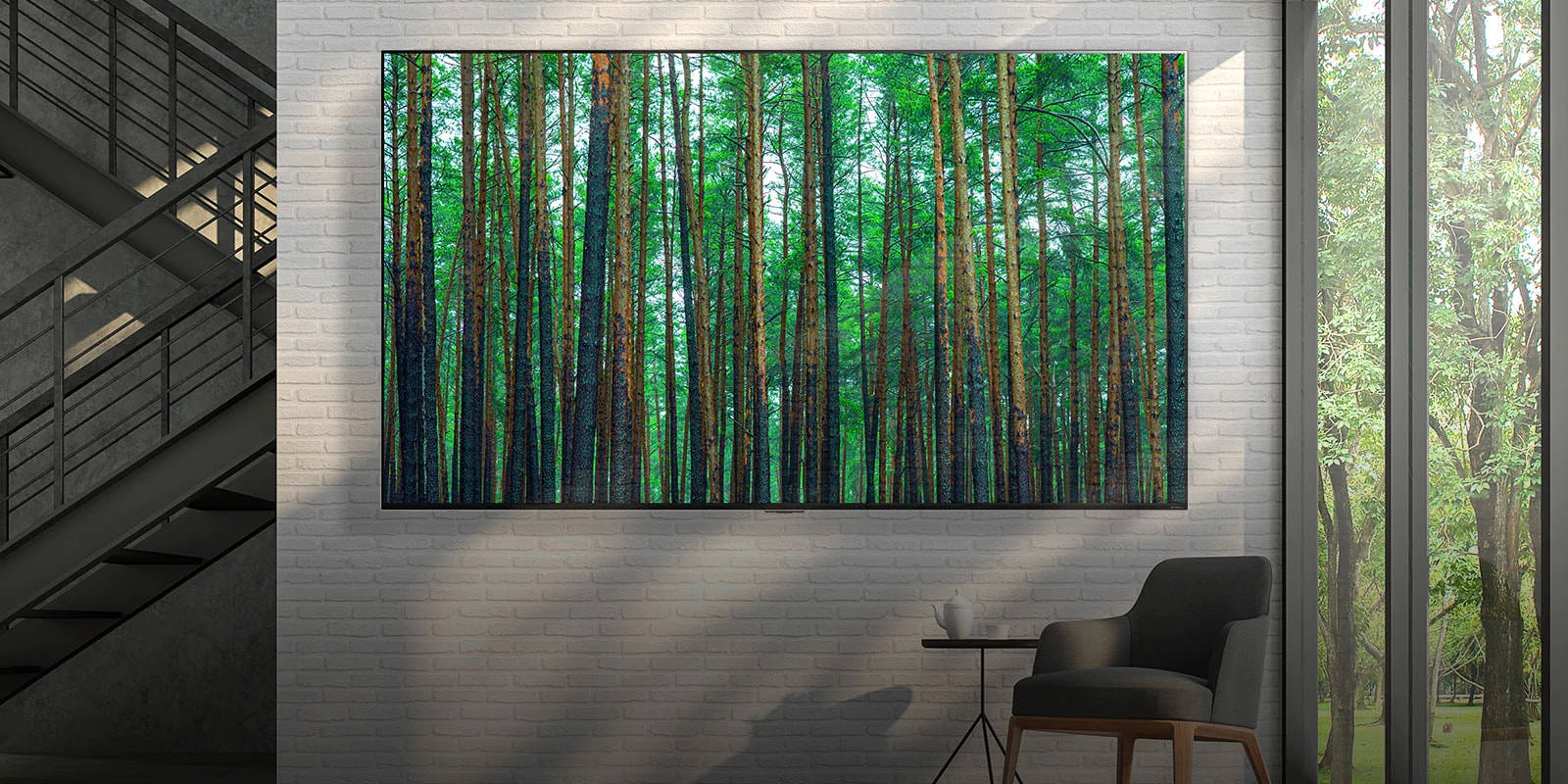 تلفزيون QNED MIni LED من إل جي كبير الحجم مثبت على جدار من الطوب الأبيض مع كرسي صغير بذراعين وطاولة في المقدمة. شاشة تعرض مشهدا لإحدى الغابات.
