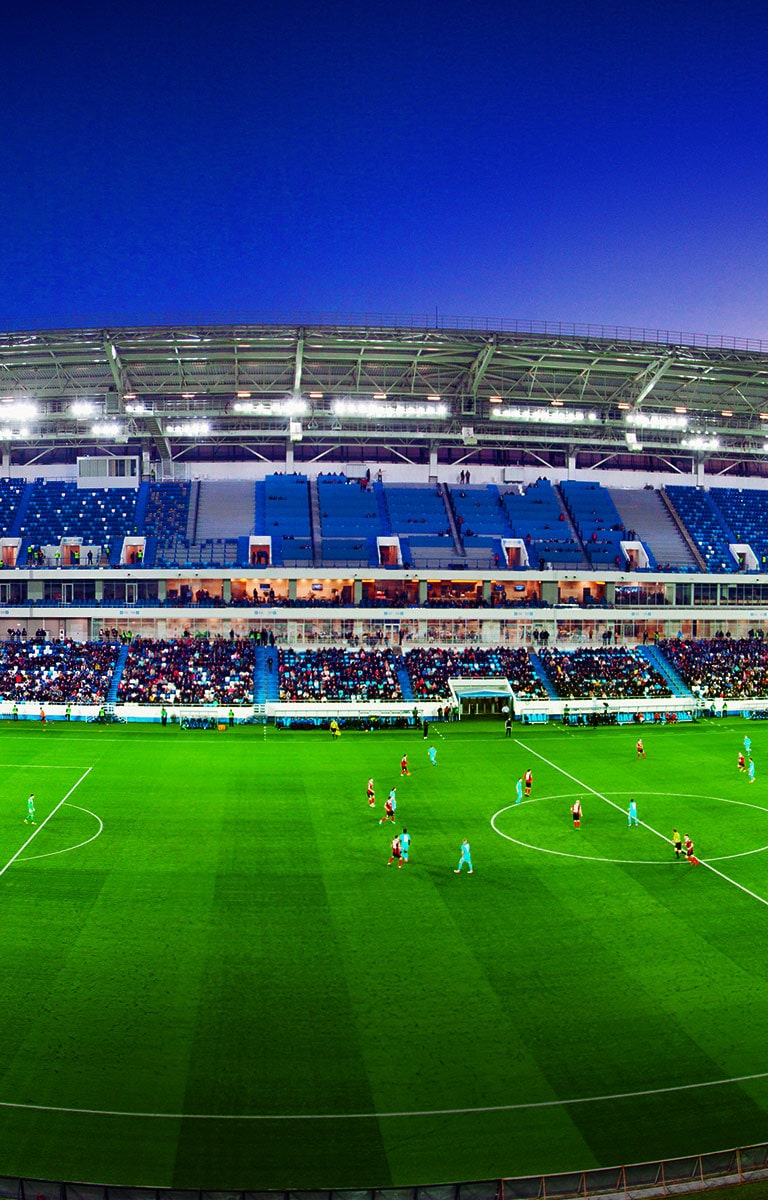 مشهد بزاوية واسعة لأحد ملاعب كرة القدم مع ظهور الجمهور يشغل كامل الحيز خلال سير أحداث المباراة.