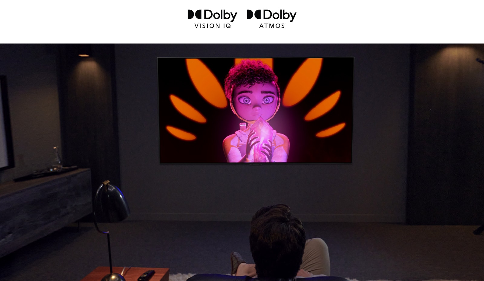 توجد شعارات Dolby Vision IQ و Atmos في خط أفقي.  أسفل الشعارات، يوجد أب وابن جالسان على الأريكة يشاهدان التلفاز يعرض   فتاة   تحمل معدنًا في منتصف خلفية سوداء وبرتقالية. 