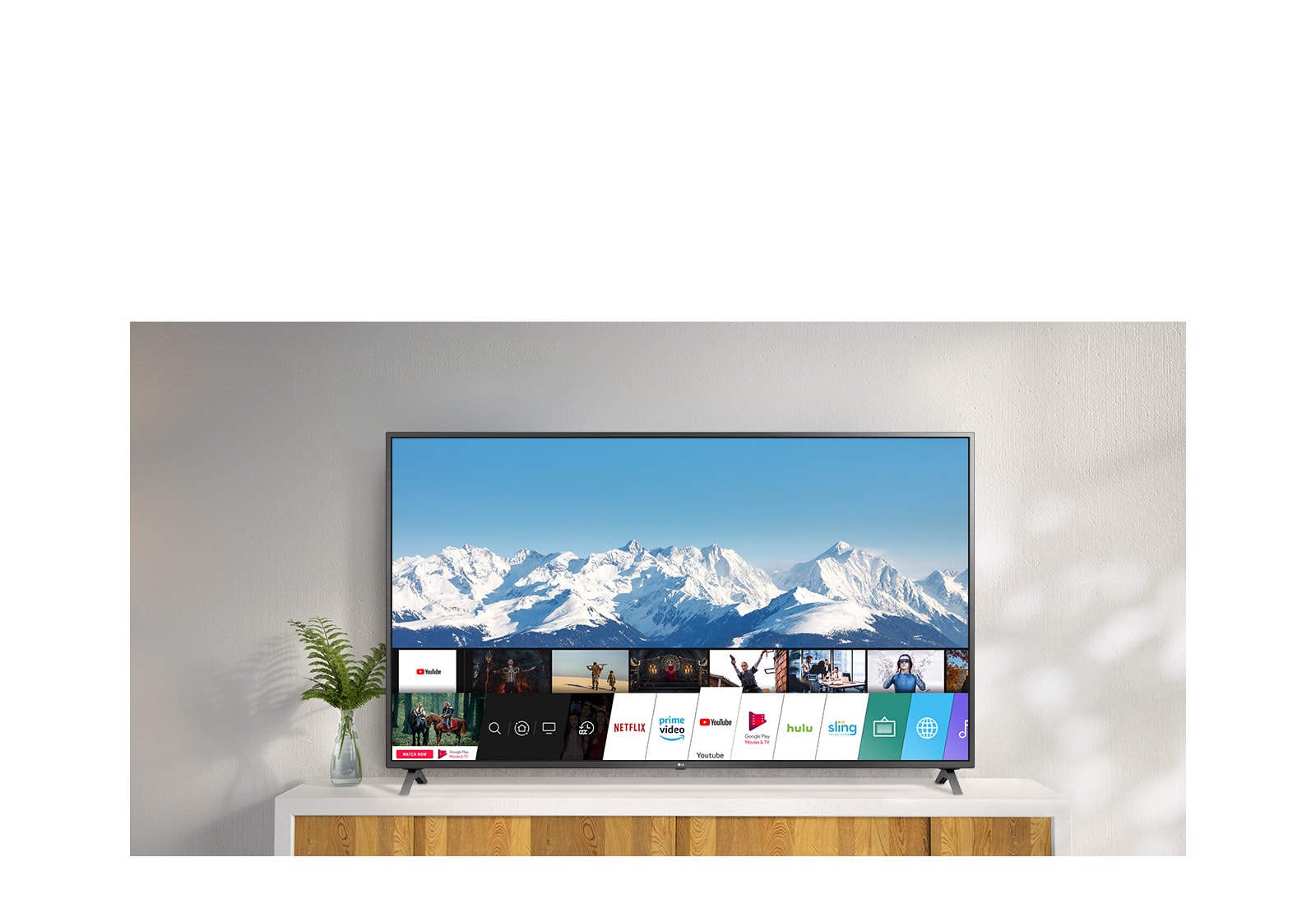 TV standing on a white stand against a white wall. TV screen shows home screen with webOS.