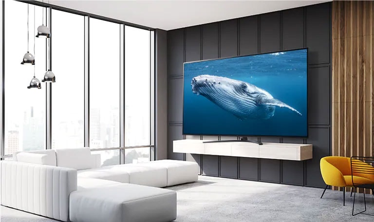 In a living room, there is a large screen TV displaying an image of a big whale in the sea.