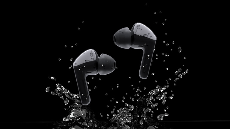 An image of two black earbuds jumping on a puddle of water