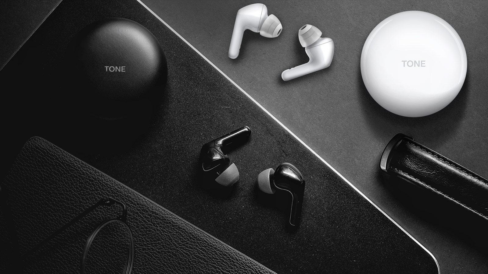 A top view of a desk with black and white earbuds and cradles sitting on top of it