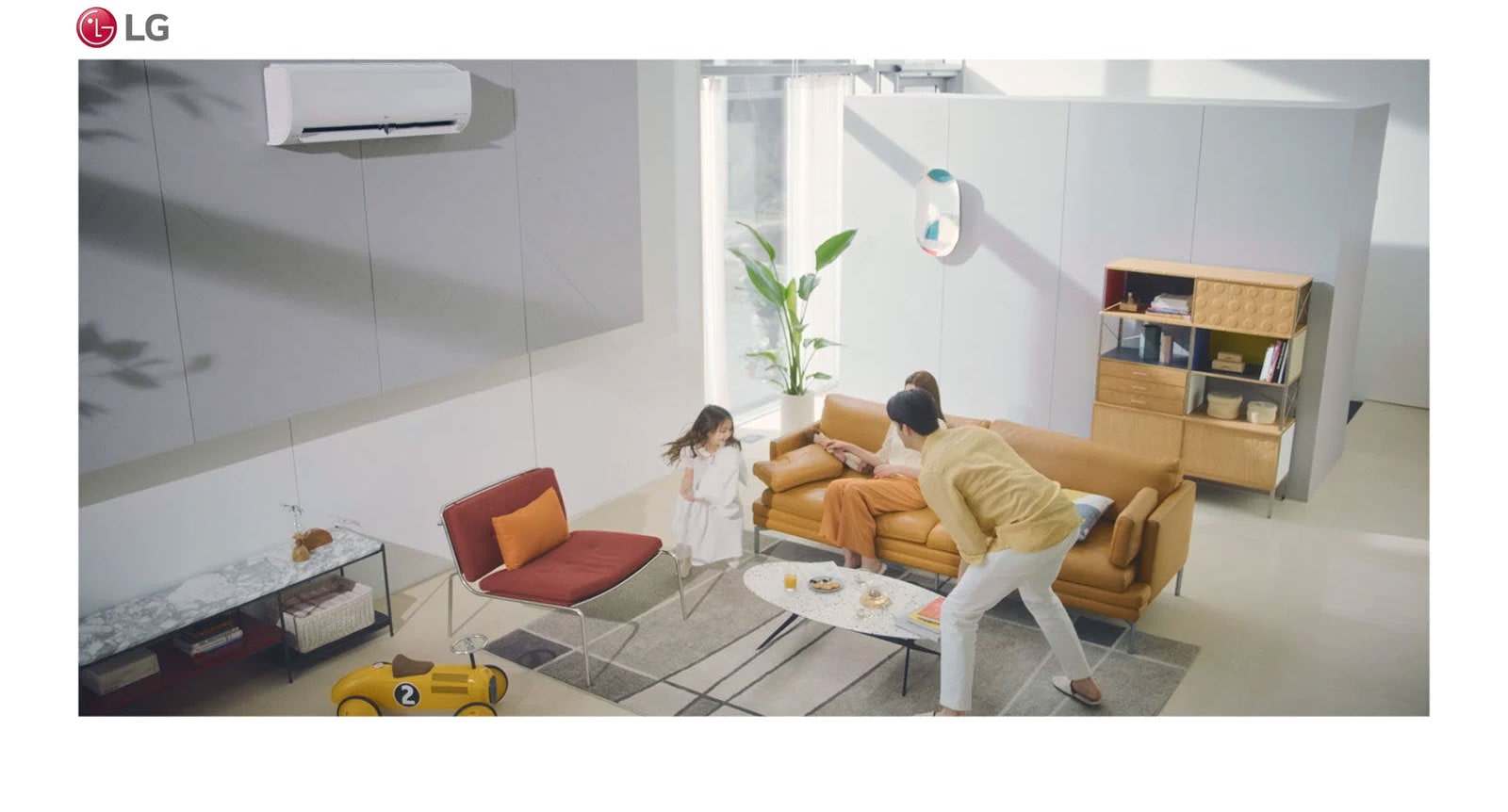 A family plays in a living room and the air condition sits in the top of the picture.