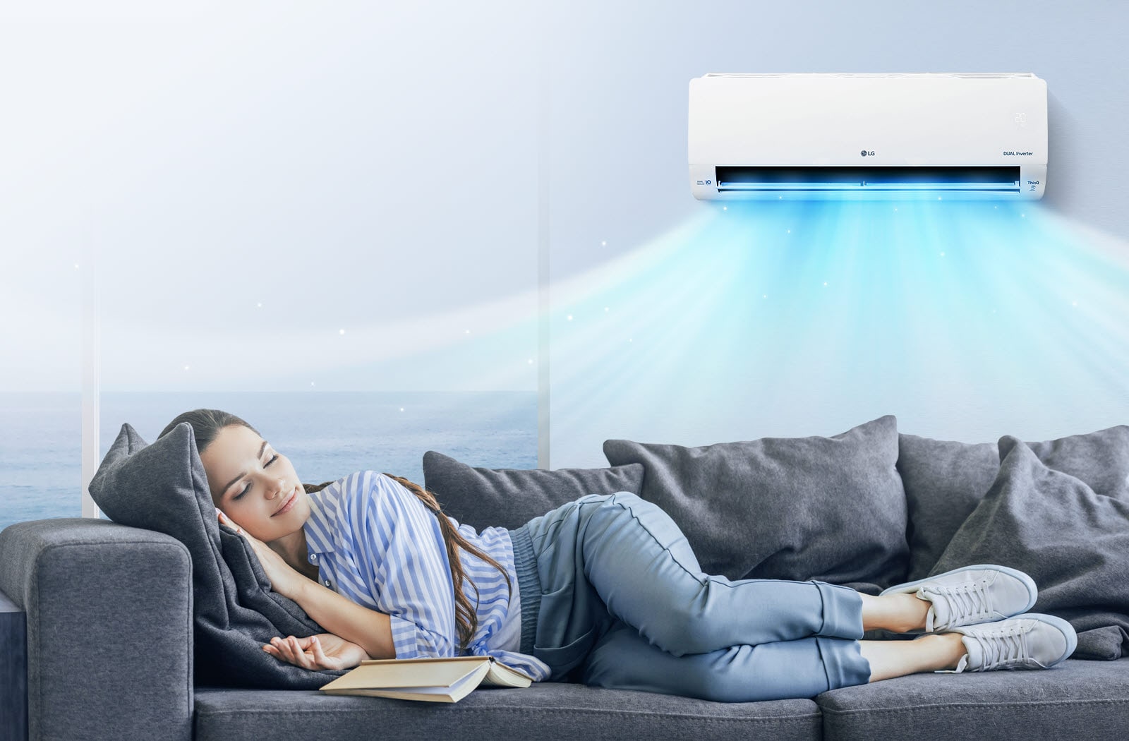 A woman rests comfortably on a couch with the air conditioner blowing air out over her.