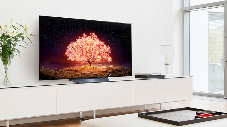 A TV displaying a shining tree in orange is in a living roomo with white interior.