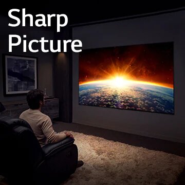 A man sitting on a couch in a dark room is watching TV displaying the rising sun behind the earth.